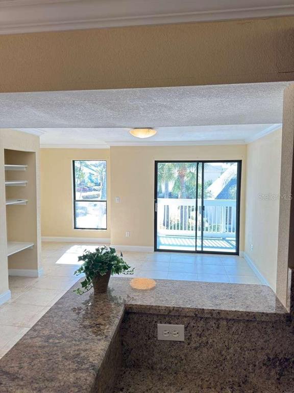 A granite countertop overlooks a living area with tile floors, a sliding glass door, and shelving — 455 ALT 19 S UNIT 12, PALM HARBOR, FL