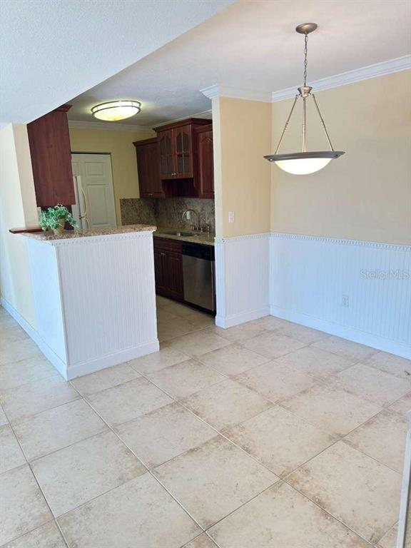 A kitchen with dark wood cabinets and tile flooring opens into a dining area — 455 ALT 19 S UNIT 12, PALM HARBOR, FL