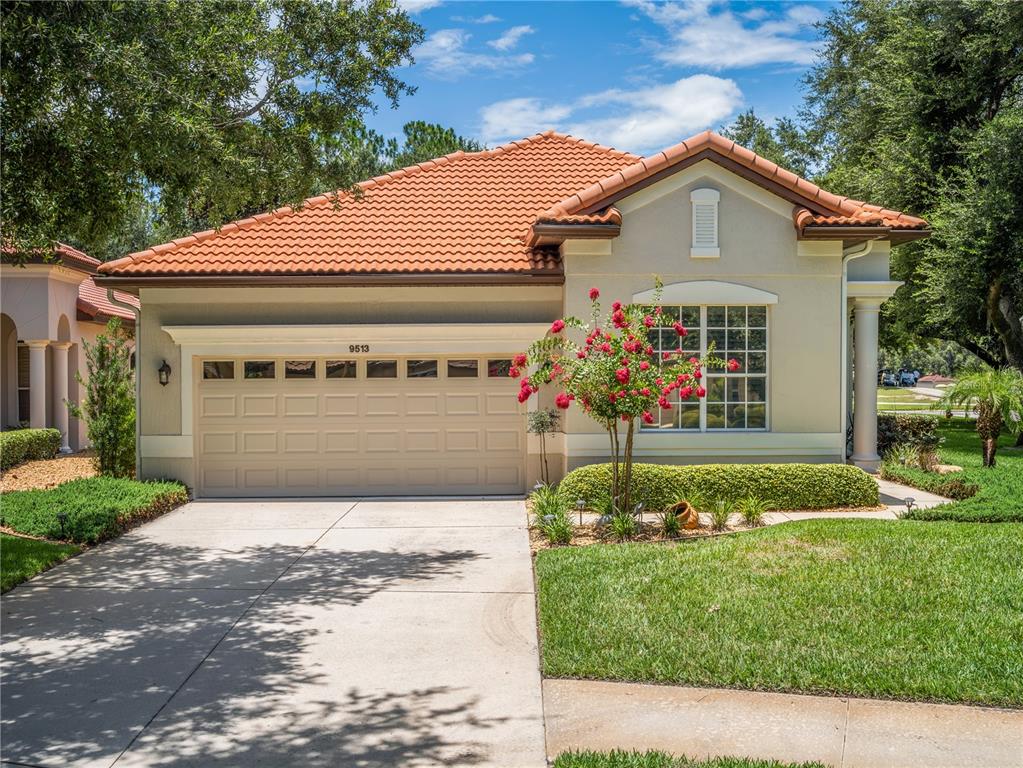 A single-story house with a beige stucco exterior, a tile roof, and a two-car garage — 9513 SERRA COURT, HOWEY IN THE HILLS, FL