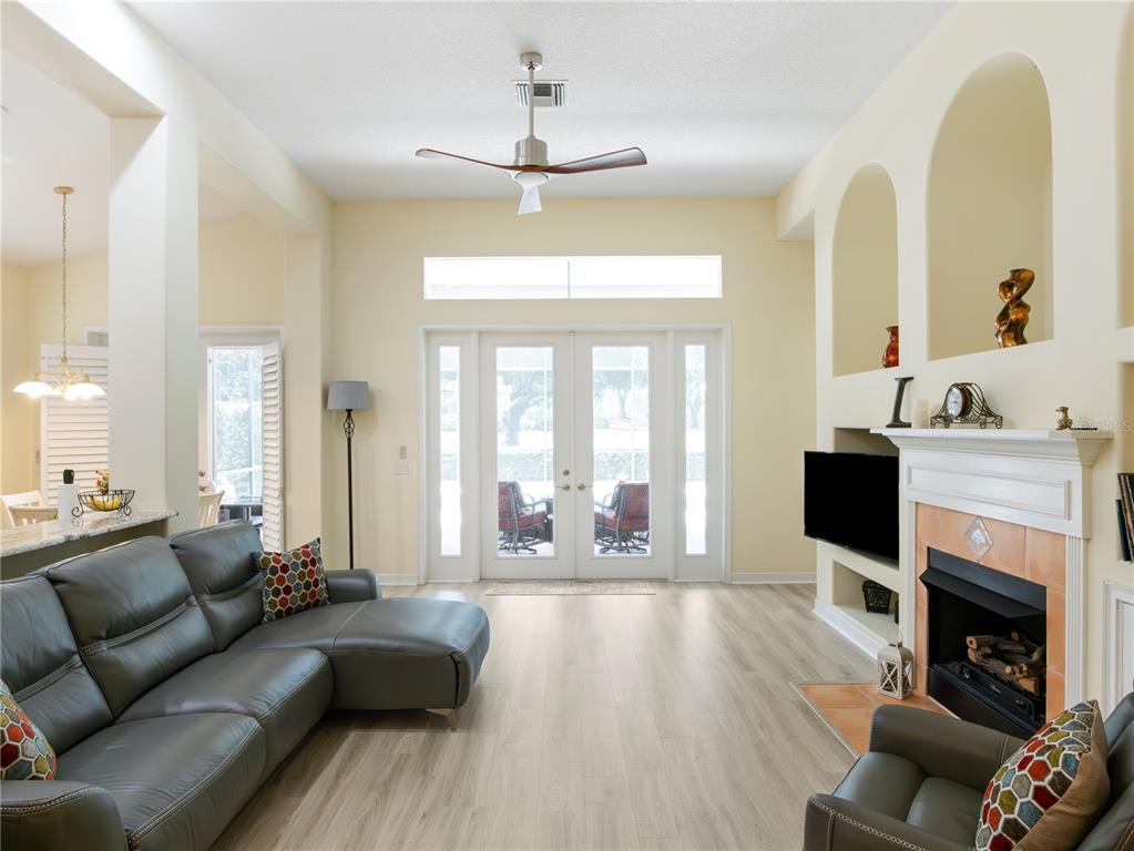 A living room features a gray sectional sofa, a fireplace, and glass doors to the outside — 9513 SERRA COURT, HOWEY IN THE HILLS, FL