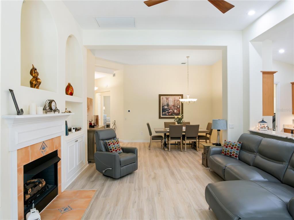 A living room with a fireplace, gray leather furniture, and an adjacent dining area — 9513 SERRA COURT, HOWEY IN THE HILLS, FL