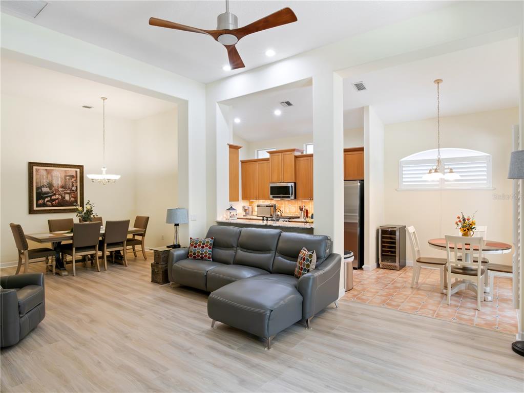 An open-concept living area features a gray sectional sofa, a dining room, and a kitchen — 9513 SERRA COURT, HOWEY IN THE HILLS, FL