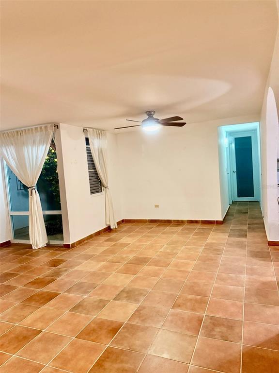 An interior room with terracotta tile flooring, a ceiling fan, and white curtains — 163 CALLE 7, CEIBA, PR