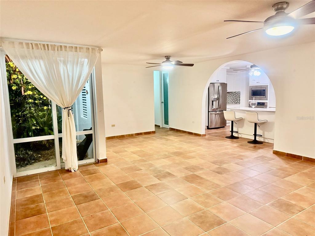 An open-concept living area features tiled floors, a ceiling fan, and an arched kitchen entryway — 163 CALLE 7, CEIBA, PR