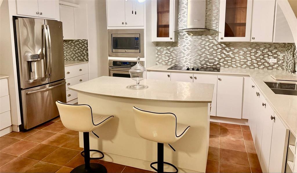 A kitchen features white cabinets, stainless steel appliances, a center island, and tiled flooring — 163 CALLE 7, CEIBA, PR