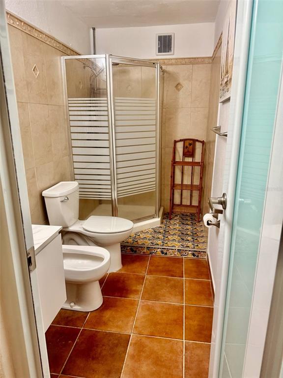 A bathroom features a corner shower, a toilet, and brown tile flooring — 163 CALLE 7, CEIBA, PR