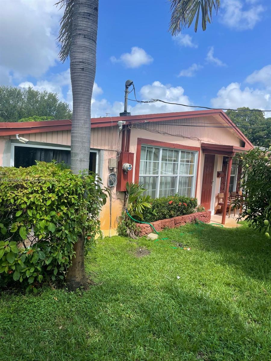 A single-story house with light-colored siding, a red-trimmed roof, and a front yard — 691 NW 20th Ct, Pompano Beach FL 33060, POMPANO BEACH, FL