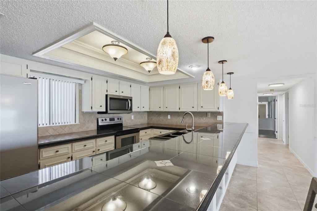 A kitchen with white cabinets, dark tile countertops, and pendant lighting over a breakfast bar — 944 S PENINSULA DRIVE UNIT 5010, DAYTONA BEACH, FL