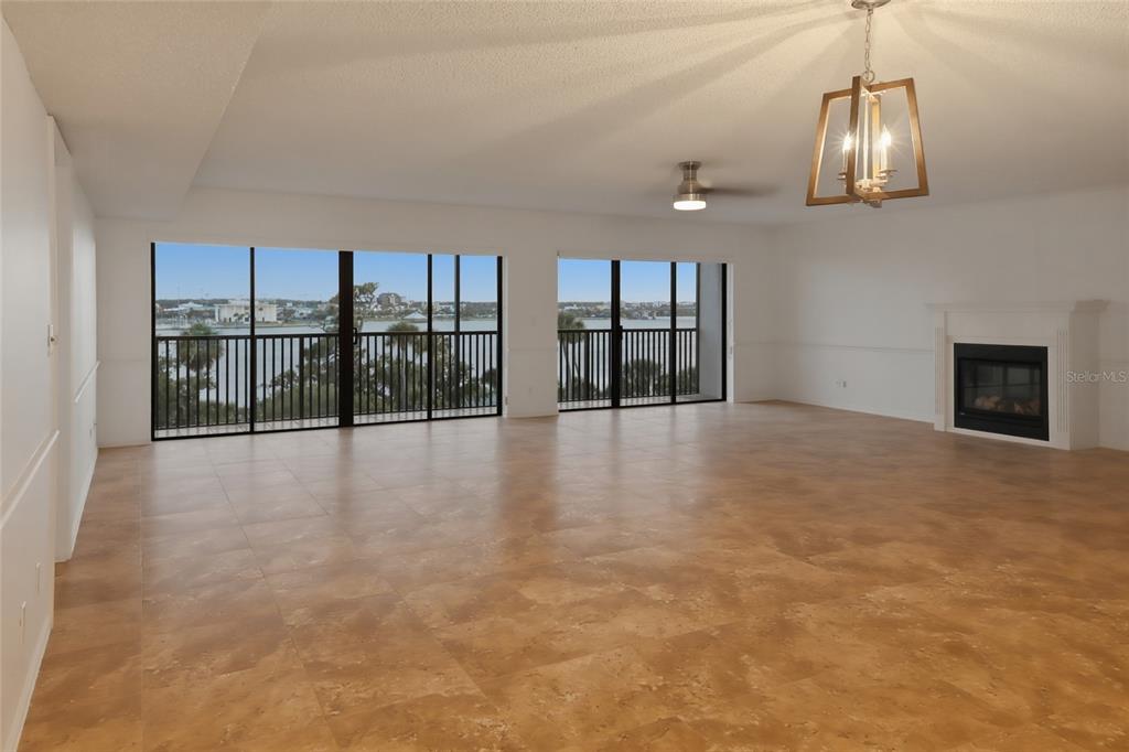 A spacious living room features tile flooring, a fireplace, and large sliding doors overlooking water — 944 S PENINSULA DRIVE UNIT 5010, DAYTONA BEACH, FL