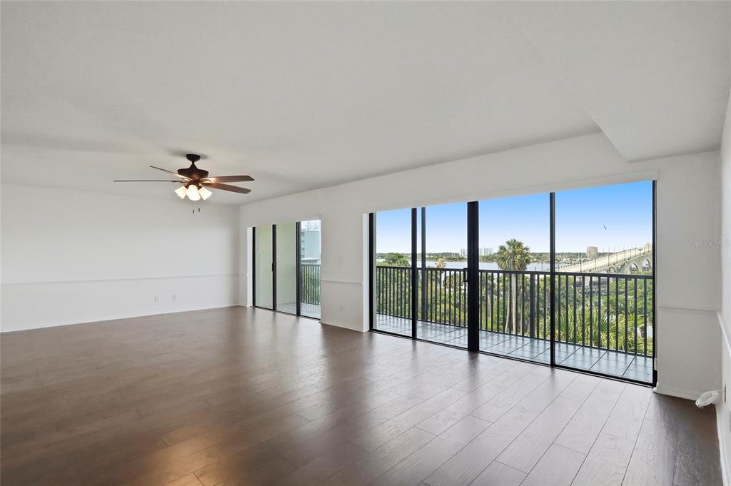 An empty living room with dark wood floors, a ceiling fan, and a balcony view — 944 S PENINSULA DRIVE UNIT 5010, DAYTONA BEACH, FL
