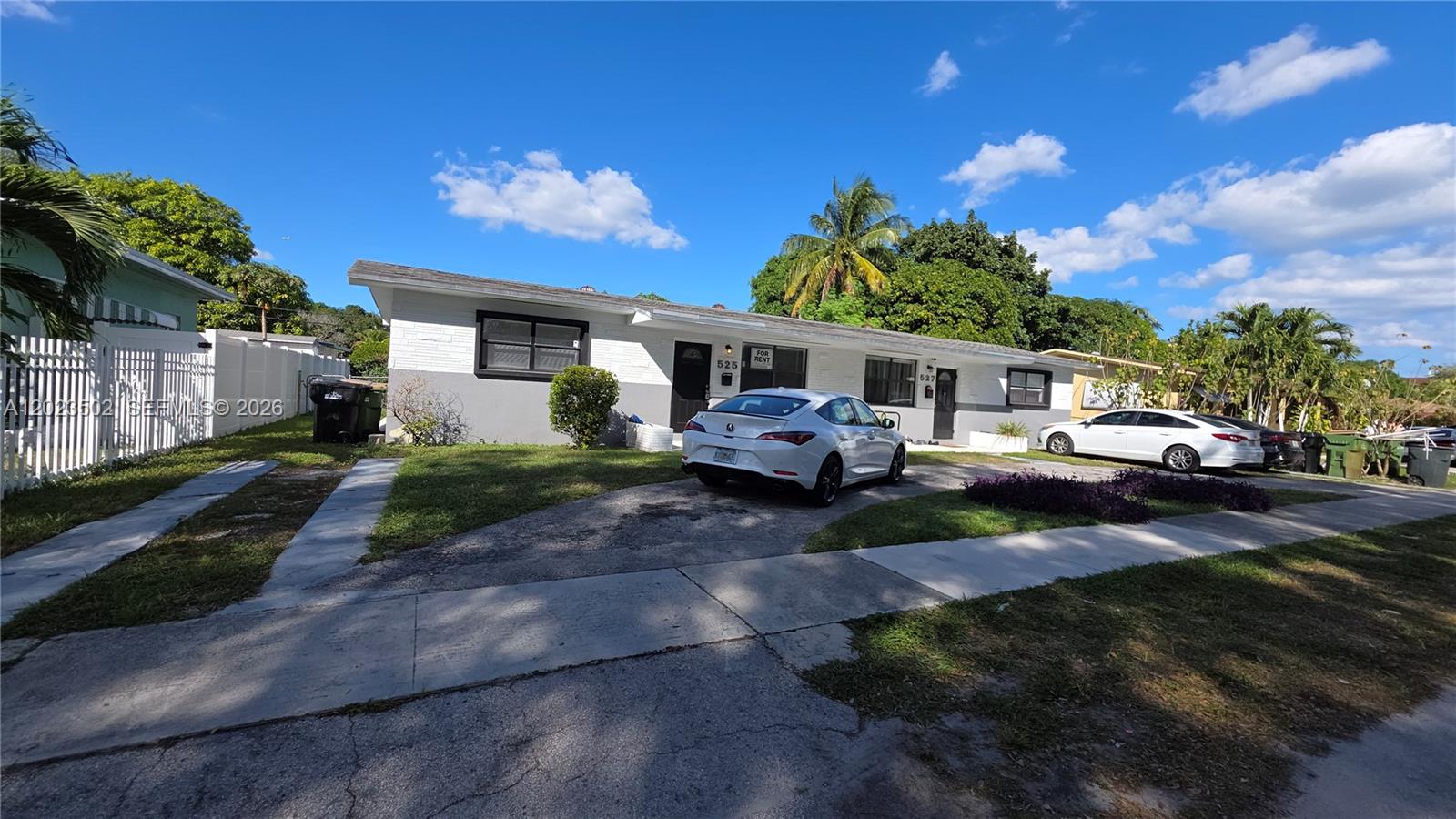 A white single-story duplex with a driveway and two parked cars under a blue sky — 525 NE 132nd Ter, North Miami FL 33161, NORTH MIAMI, FL