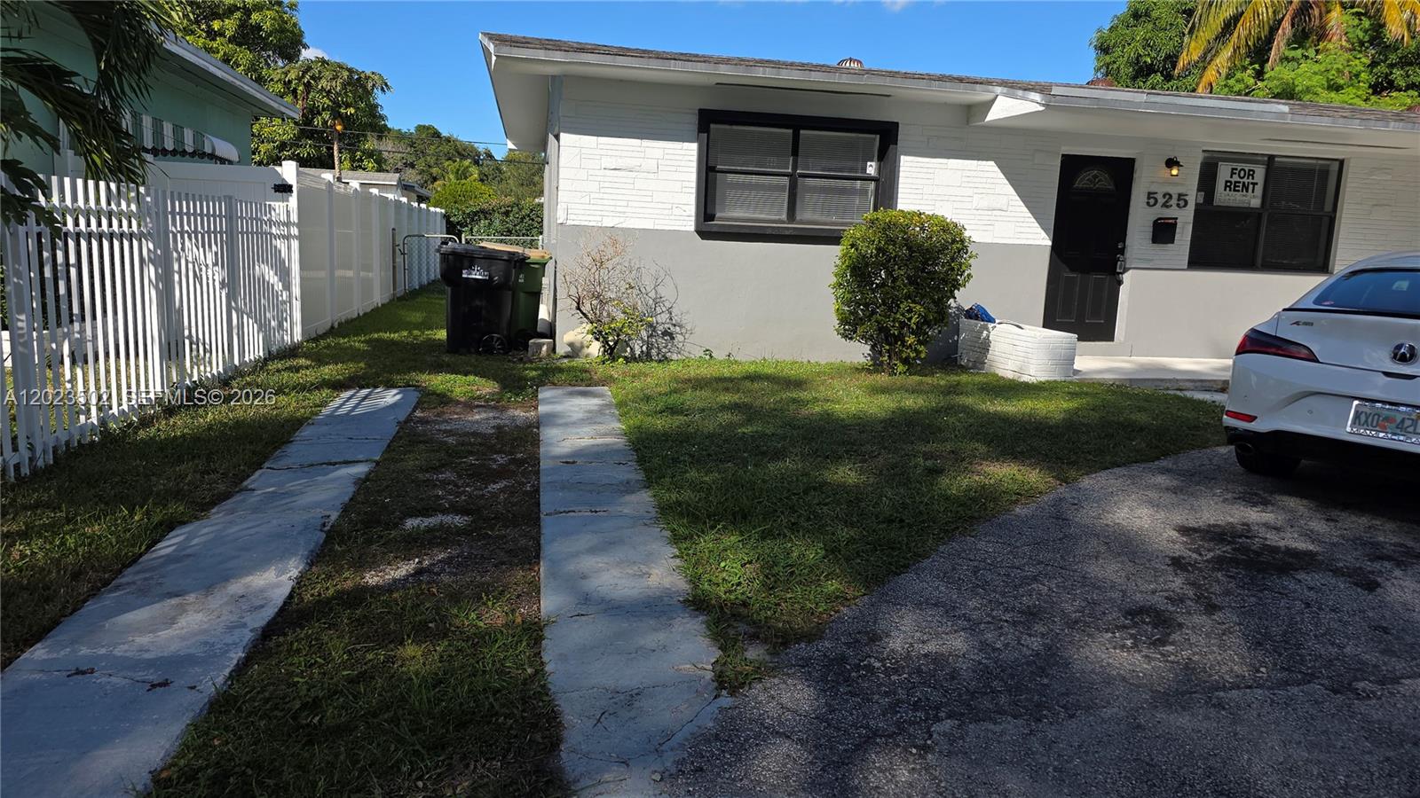 A single-story house with a white brick facade, a black door, and a paved driveway — 525 NE 132nd Ter, North Miami FL 33161, NORTH MIAMI, FL