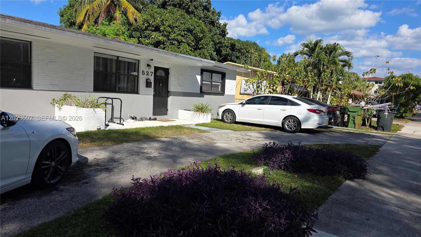 A white single-story house features a gray lower exterior, a black door, and a driveway — 525 NE 132nd Ter, North Miami FL 33161, NORTH MIAMI, FL