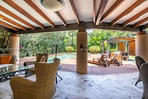 A covered patio with wicker furniture overlooks a swimming pool and lush tropical landscaping — 800 S Del Cementerio, CR 0000, CR
