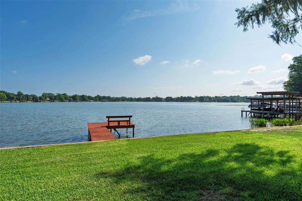 A grassy lawn leads to a wooden dock on a lake with a boat house — 2655 LAKE SHORE DRIVE, ORLANDO, FL