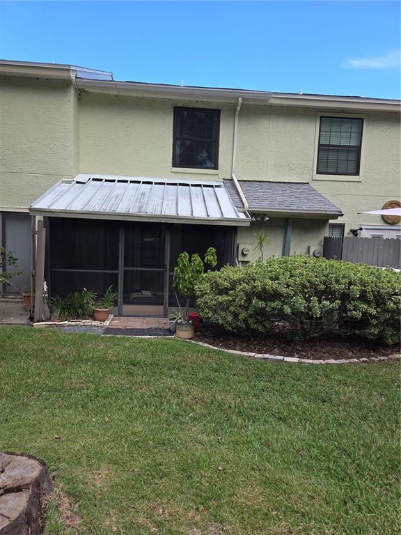 A backyard view of a two-story townhouse with a screened-in patio and metal roof — 1701 SE 24TH ROAD UNIT 103, OCALA, FL