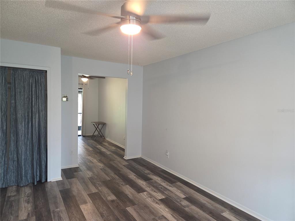 An interior view of a room with light blue walls, wood-look flooring, and a ceiling fan — 1701 SE 24TH ROAD UNIT 103, OCALA, FL