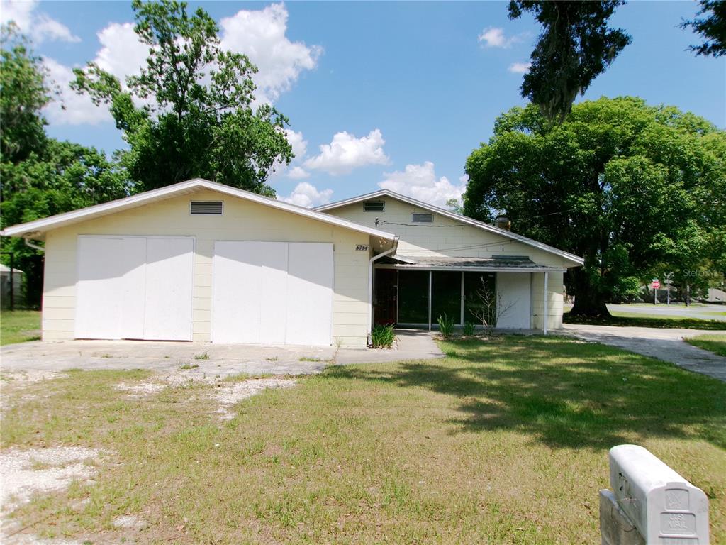 A single-story house with a two-car garage, light siding, and a covered front porch — 5714 19TH STREET, ZEPHYRHILLS, FL