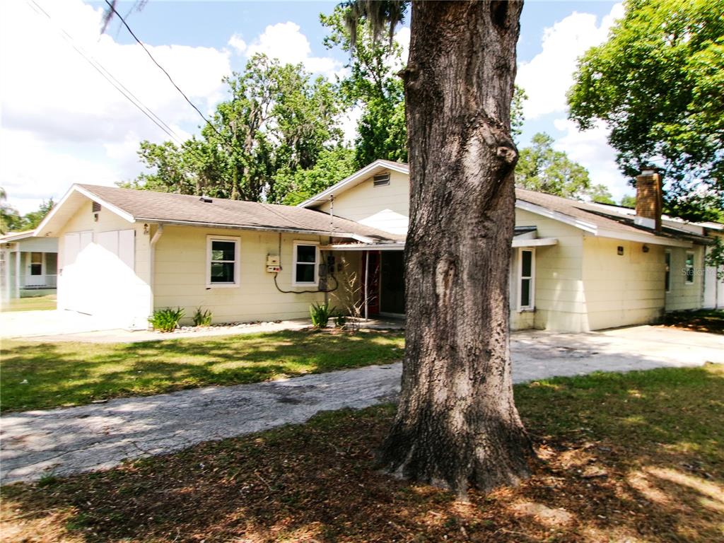A single-story house with light yellow siding, a garage, and a large tree in front — 5714 19TH STREET, ZEPHYRHILLS, FL