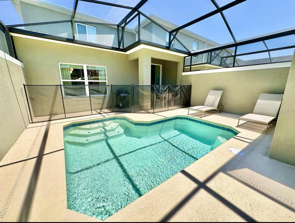 A screened-in patio features a small swimming pool, two lounge chairs, and a safety fence — 2580 READING TRAIL, KISSIMMEE, FL