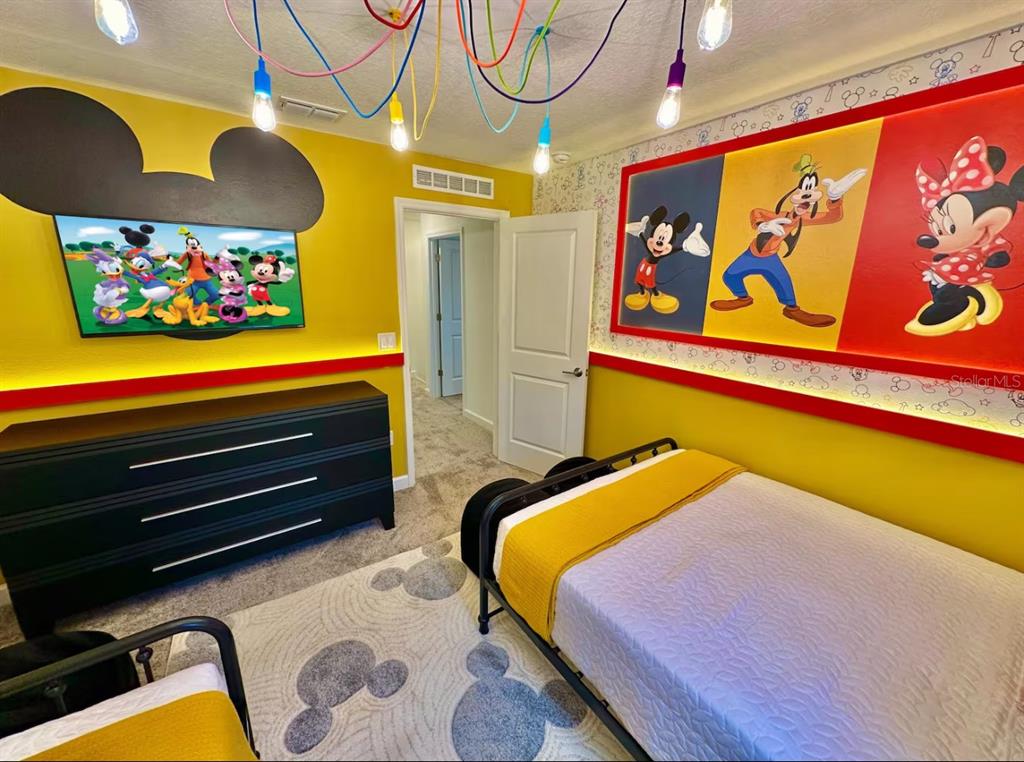 A bedroom features Mickey Mouse-themed decor, a television, a bed, and a patterned area rug — 2580 READING TRAIL, KISSIMMEE, FL