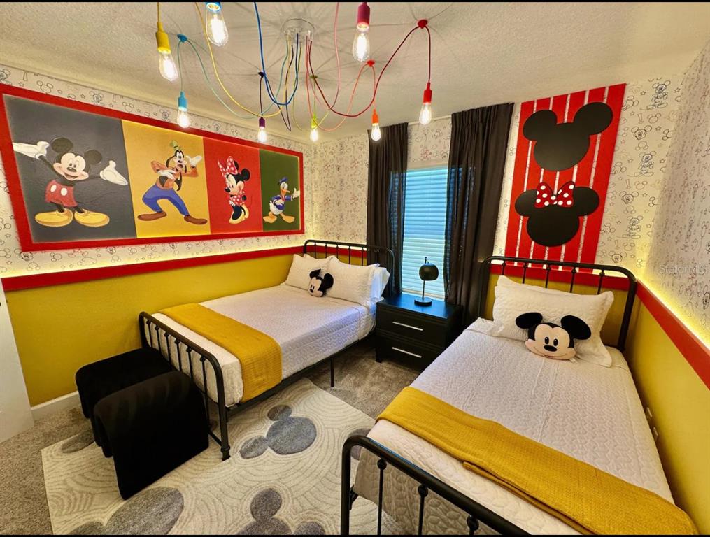 A bedroom with two twin beds, Mickey Mouse-themed decor, and a colorful pendant light fixture — 2580 READING TRAIL, KISSIMMEE, FL