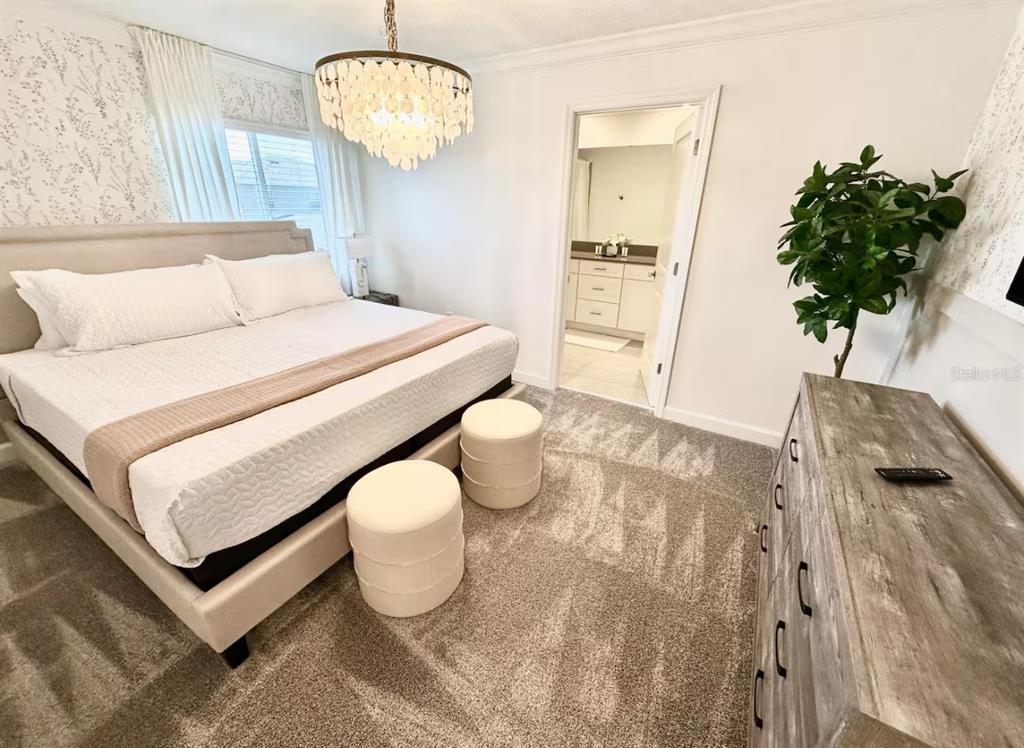 A bedroom features a king bed, a chandelier, two ottomans, and an attached bathroom — 2580 READING TRAIL, KISSIMMEE, FL