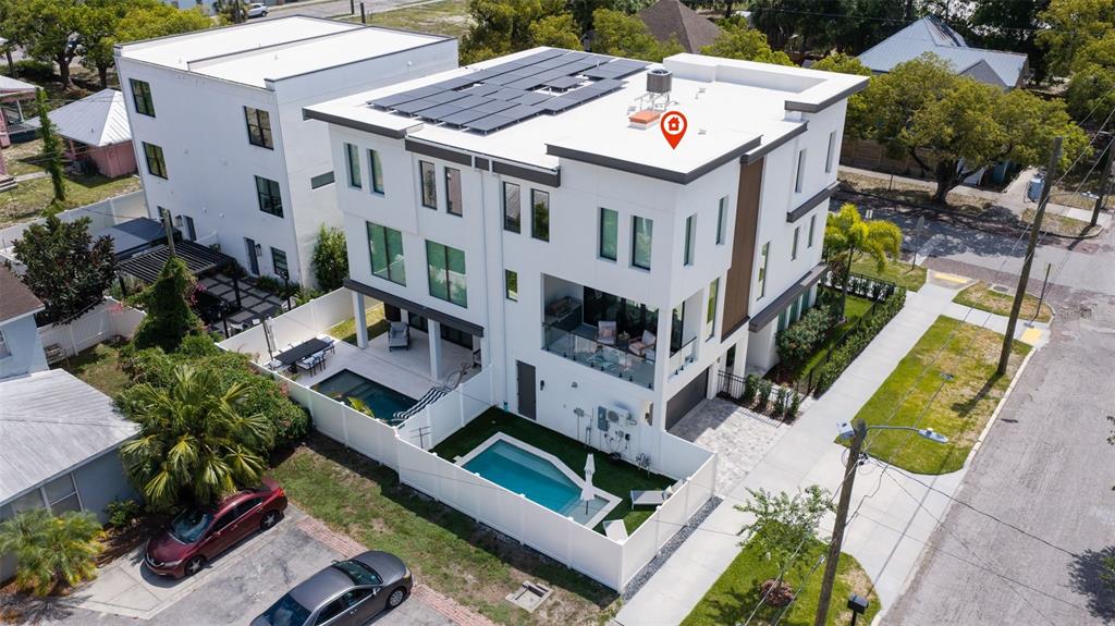 An aerial view shows a modern three-story white townhouse with a rooftop solar array and pool — 2502 N HIGHLAND AVENUE UNIT 1, TAMPA, FL