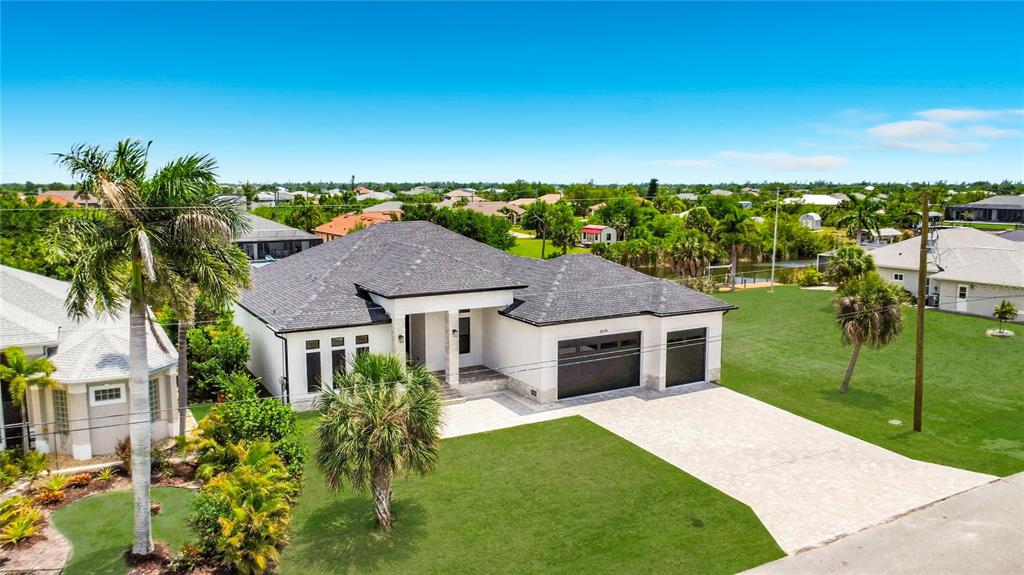 An aerial view shows a single-story house with a dark roof and a paved driveway — 9524 SINGER CIRCLE, PORT CHARLOTTE, FL