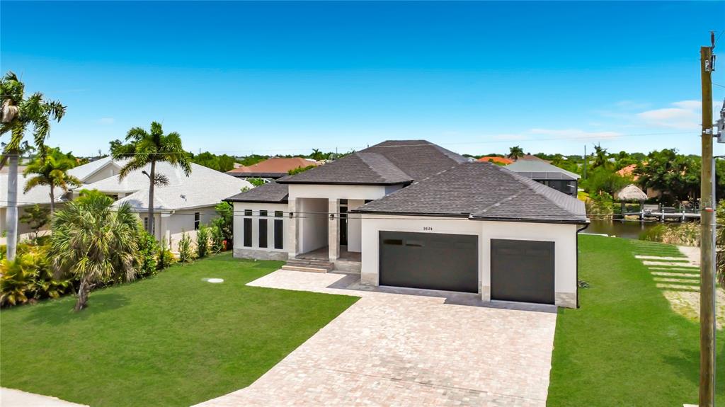 A modern single-story house with a dark roof, white exterior, and a paved driveway — 9524 SINGER CIRCLE, PORT CHARLOTTE, FL