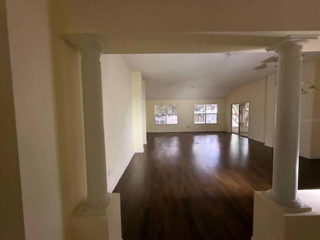 An open living area features dark hardwood floors and two prominent white decorative columns — 1109 MONTEREY LANE, LADY LAKE, FL