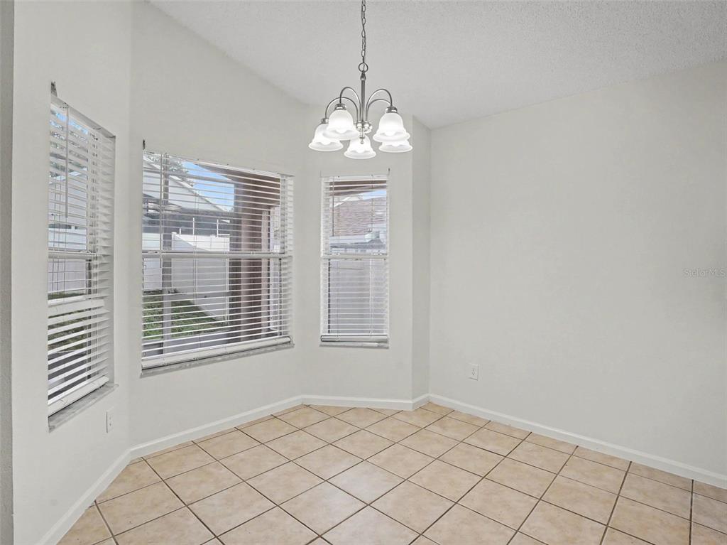 A dining area with tile flooring, a chandelier, and windows with white blinds — 15854 BAY VISTA DRIVE, CLERMONT, FL