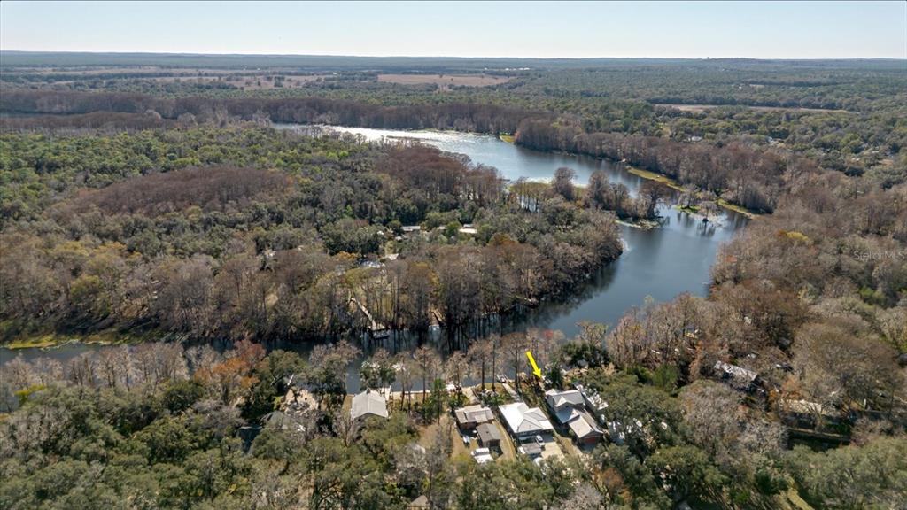 An aerial view shows a house with a yellow arrow situated along a riverbank — 28330 PETERSON CAMP ROAD, BROOKSVILLE, FL