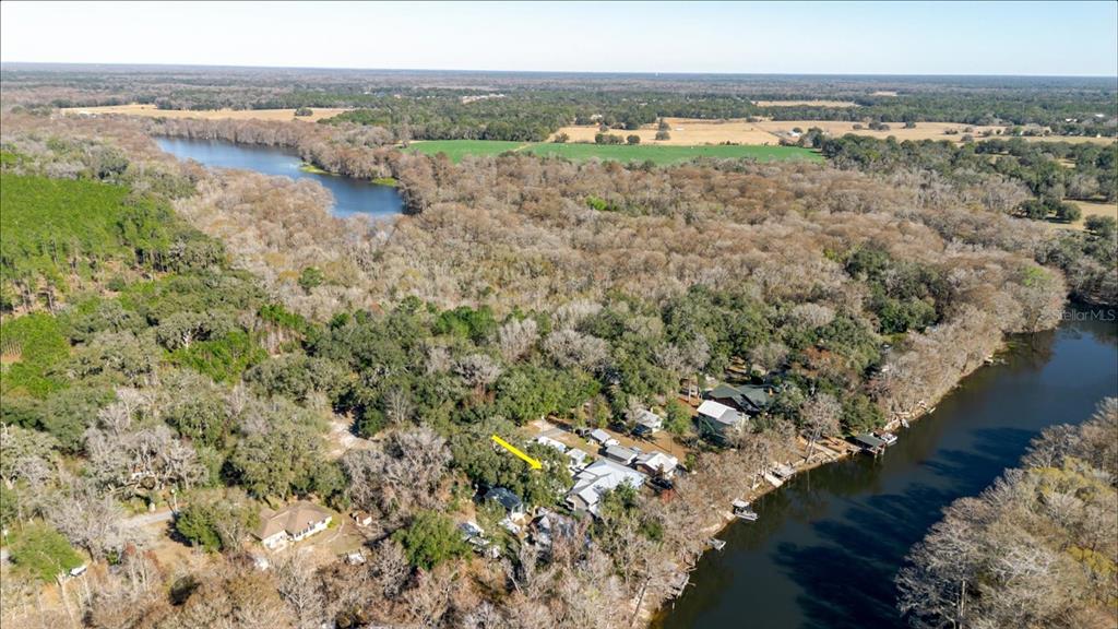 An aerial view shows a house nestled in a wooded area beside a river — 28330 PETERSON CAMP ROAD, BROOKSVILLE, FL