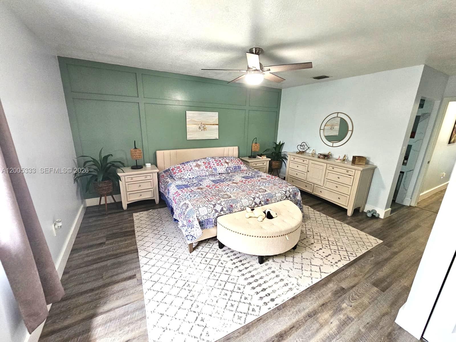 A bedroom features a green paneled accent wall, a patterned quilt, and light-colored furniture — 15429 SW 92nd St, Miami FL 33196, MIAMI, FL