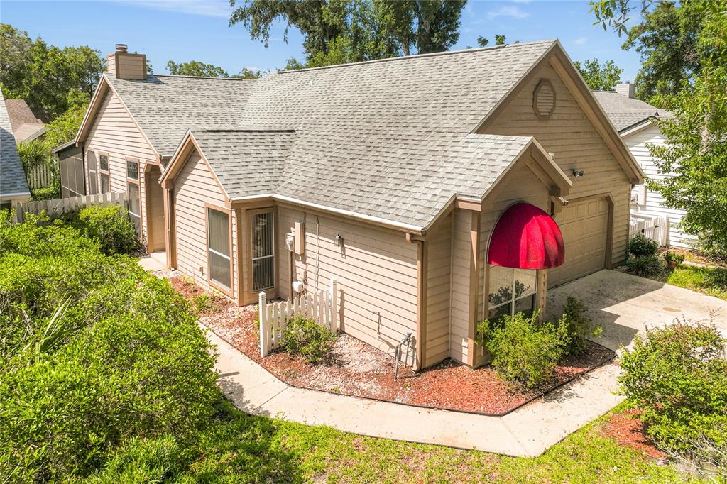 An exterior view of a tan, single-story house with a red awning over a window — 278 BLACKWATER PLACE, LONGWOOD, FL