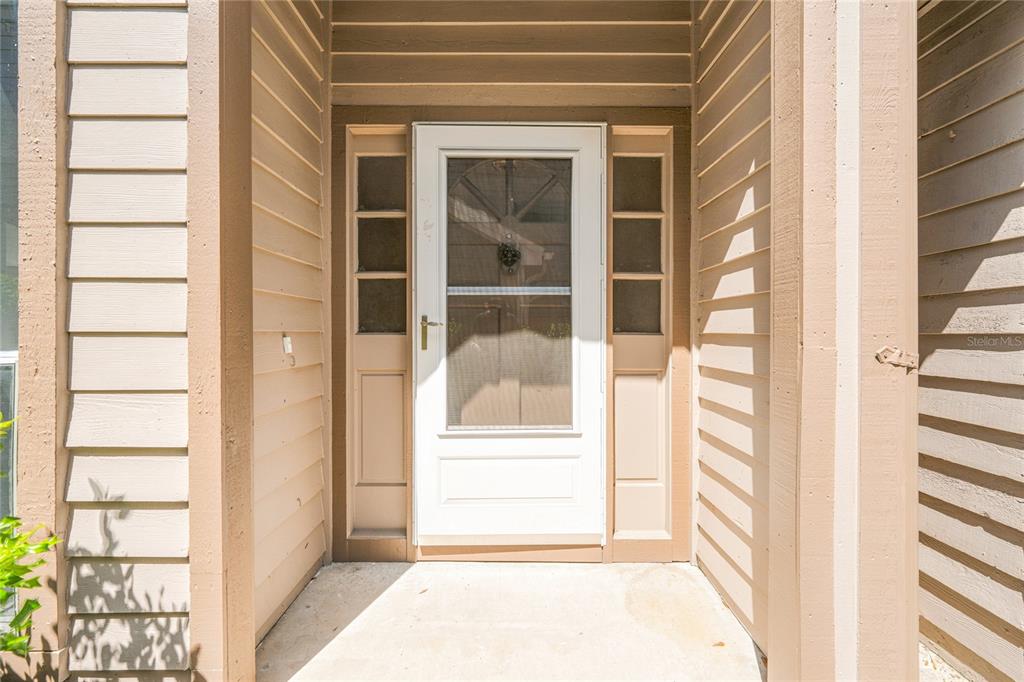 A white storm door is centered between two sidelights on a tan exterior entryway — 278 BLACKWATER PLACE, LONGWOOD, FL