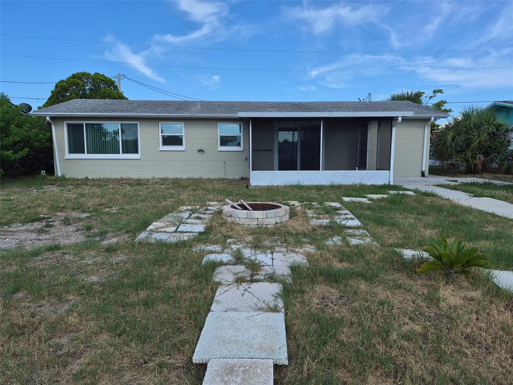 The exterior of a single-story house features a screened-in porch and a stone fire pit — 13636 VERONICA DRIVE, HUDSON, FL