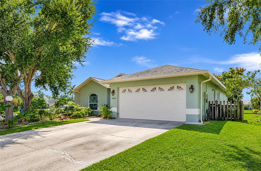 A light green single-story house features a two-car garage and a concrete driveway — 2405 ICECAPADE DRIVE, SARASOTA, FL