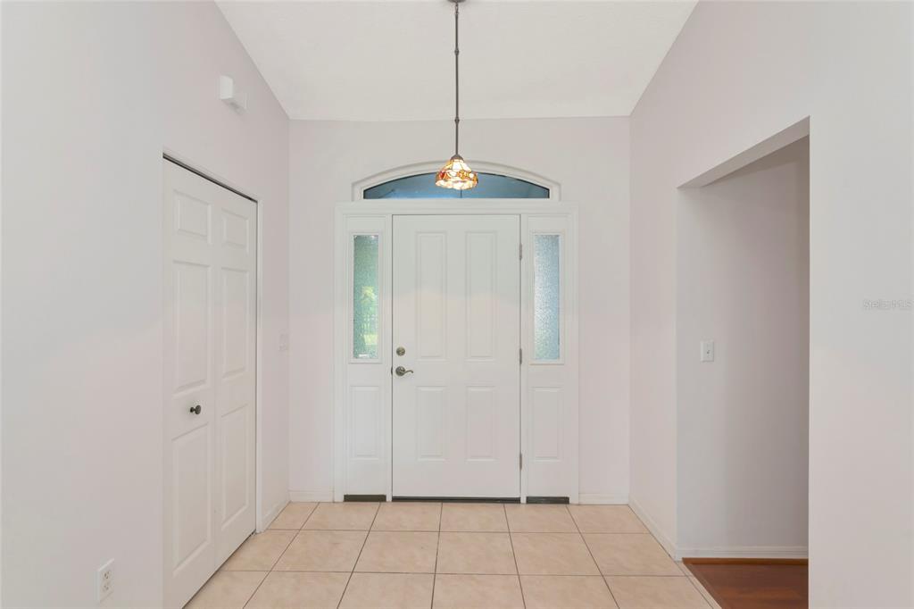 An entryway features a white front door with sidelights, tile flooring, and a hanging light — 2405 ICECAPADE DRIVE, SARASOTA, FL