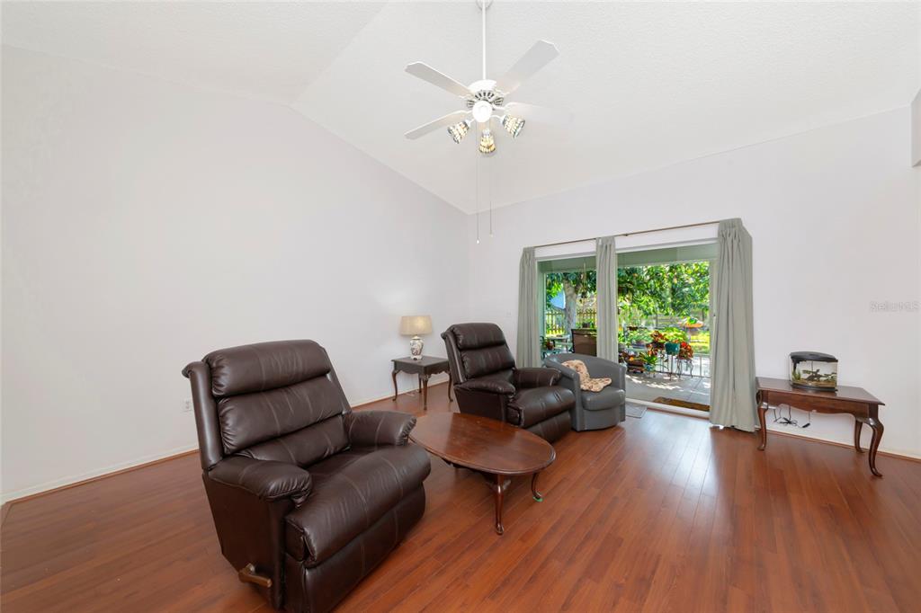 A living room features dark wood flooring, two leather recliners, and sliding glass patio doors — 2405 ICECAPADE DRIVE, SARASOTA, FL