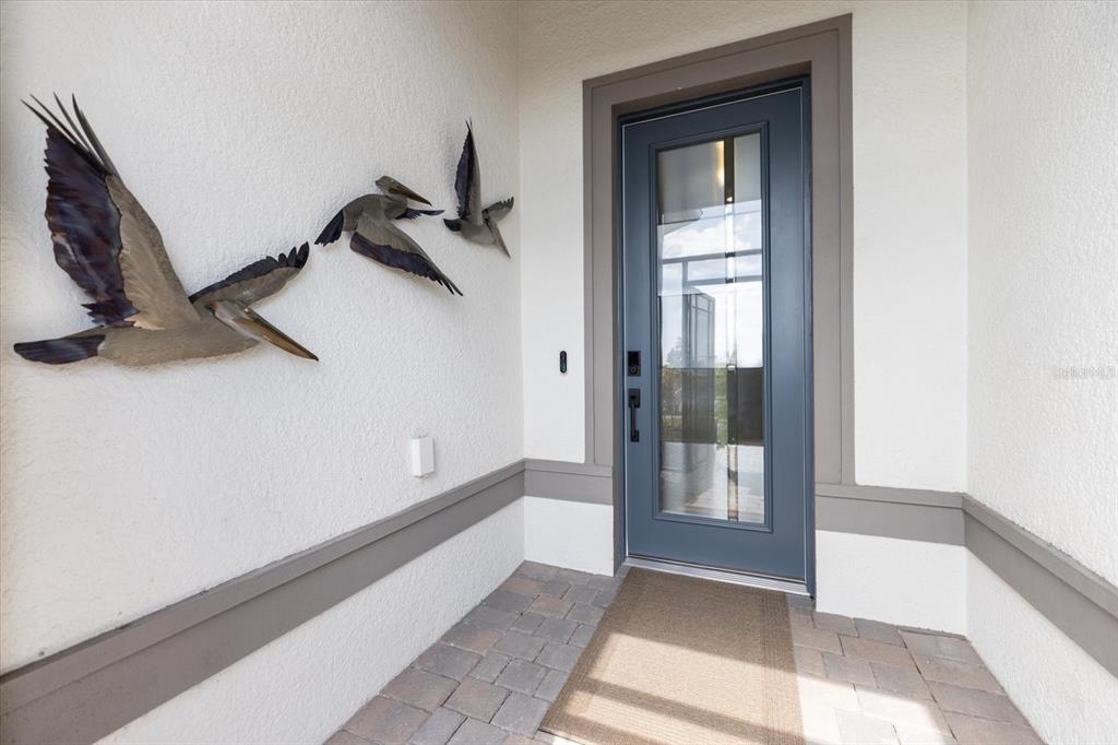 A front entryway features a blue glass-paneled door and three metal pelican wall sculptures — 10333 BLUE RUNNER DRIVE, ENGLEWOOD, FL