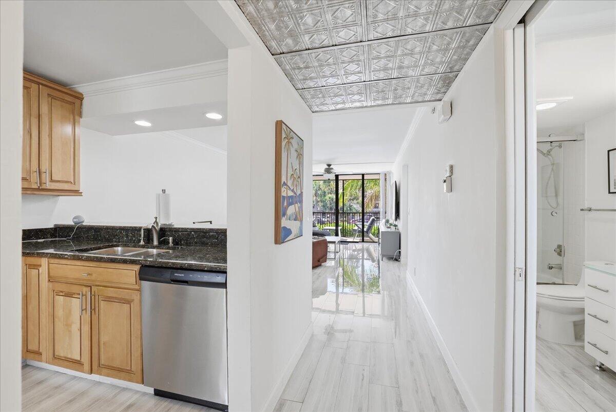 A kitchen with wood cabinets and granite countertops opens to a hallway with tiled floors — 16 Royal Palm Way # 205, Boca Raton FL 33432, BOCA RATON, FL