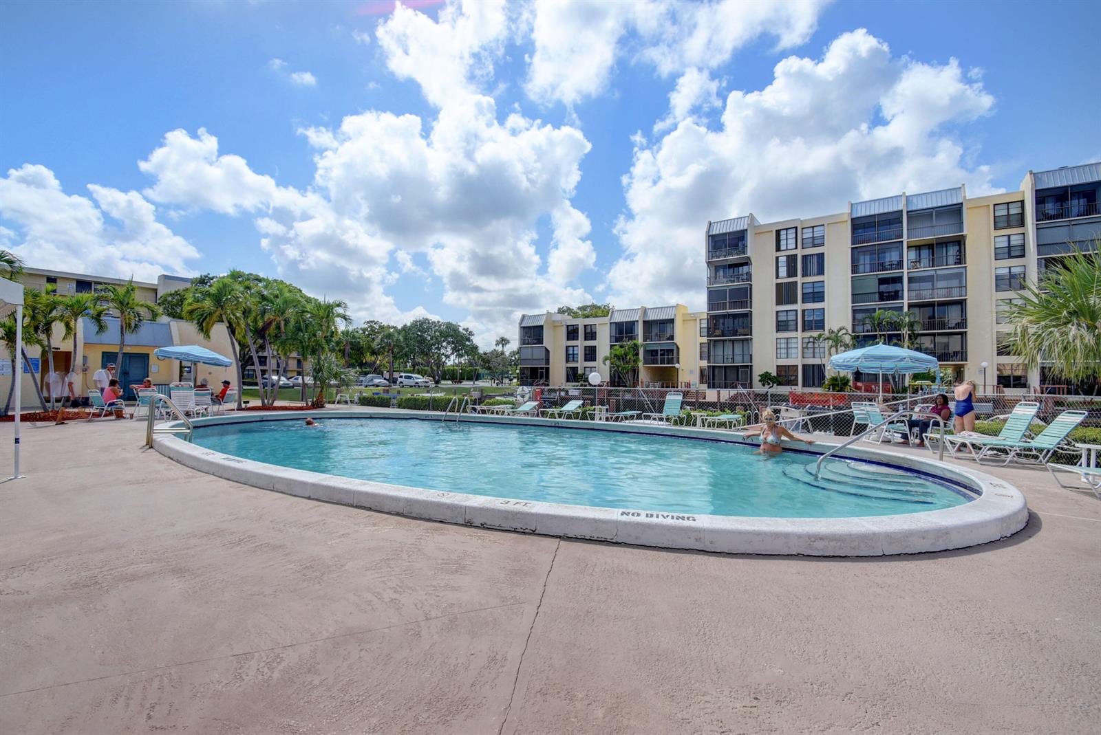 An oval swimming pool sits on a concrete deck in front of multi-story apartment buildings — 16 Royal Palm Way # 205, Boca Raton FL 33432, BOCA RATON, FL