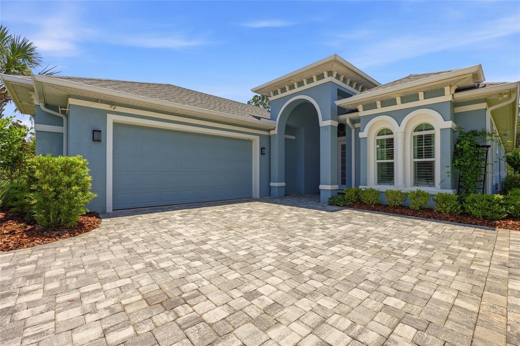 A blue single-story house with a paved driveway, arched entryway, and two-car garage — 296 S RIVERWALK DRIVE, PALM COAST, FL