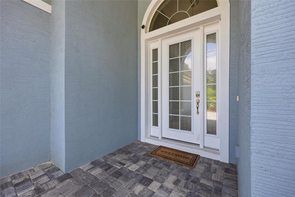 A front entryway features a white door with glass panels, a transom window, and pavers — 296 S RIVERWALK DRIVE, PALM COAST, FL