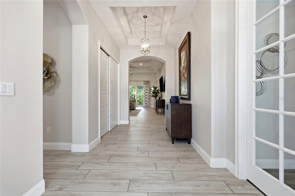 A bright hallway features light wood-look tile flooring, a coffered ceiling, and an arched entryway — 296 S RIVERWALK DRIVE, PALM COAST, FL