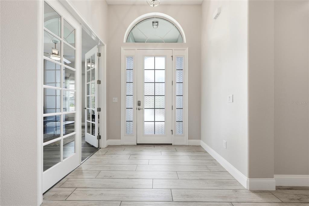 A bright entryway features light wood-look tile flooring, a glass-paneled front door, and French doors — 296 S RIVERWALK DRIVE, PALM COAST, FL