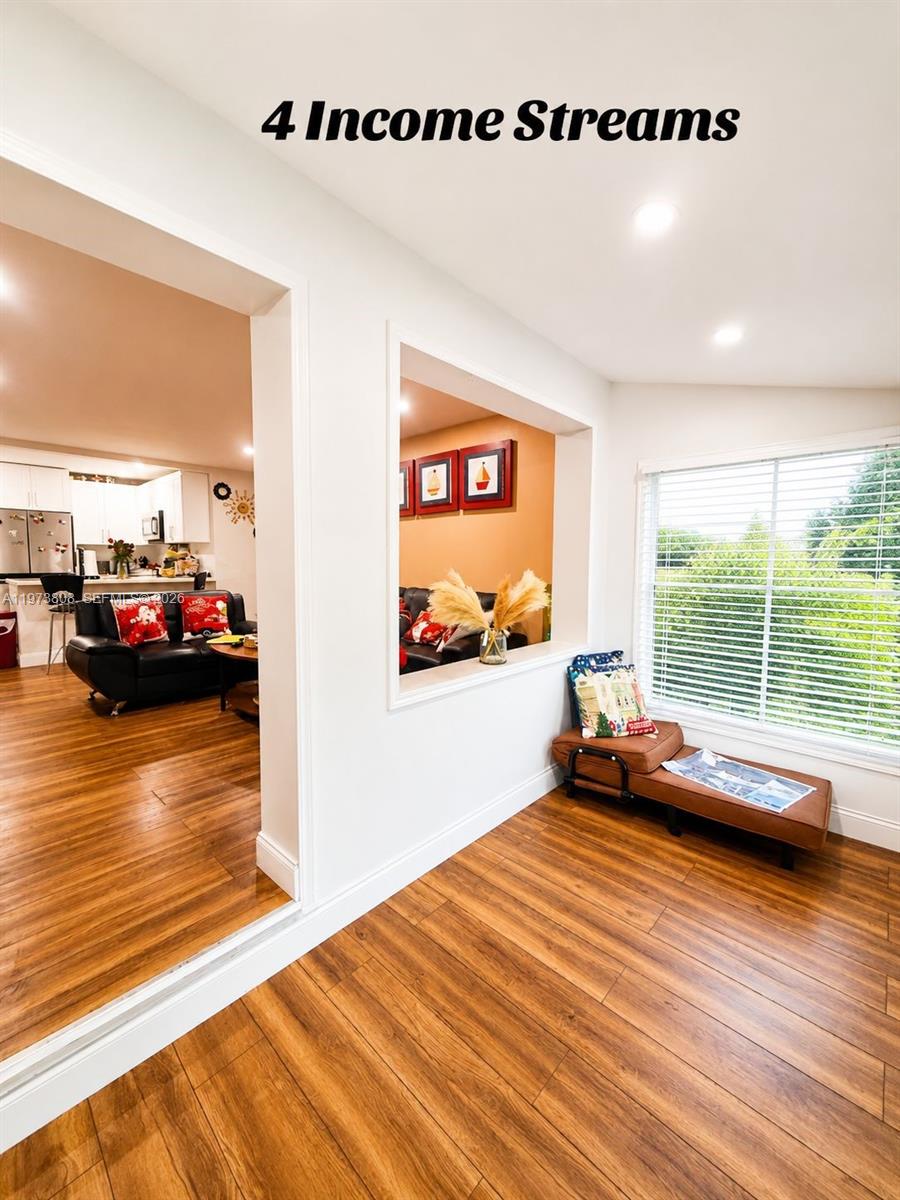 A living room with wood-look flooring features a pass-through window looking into a kitchen — 2281 NW 81st Ter, Miami FL 33147, MIAMI, FL
