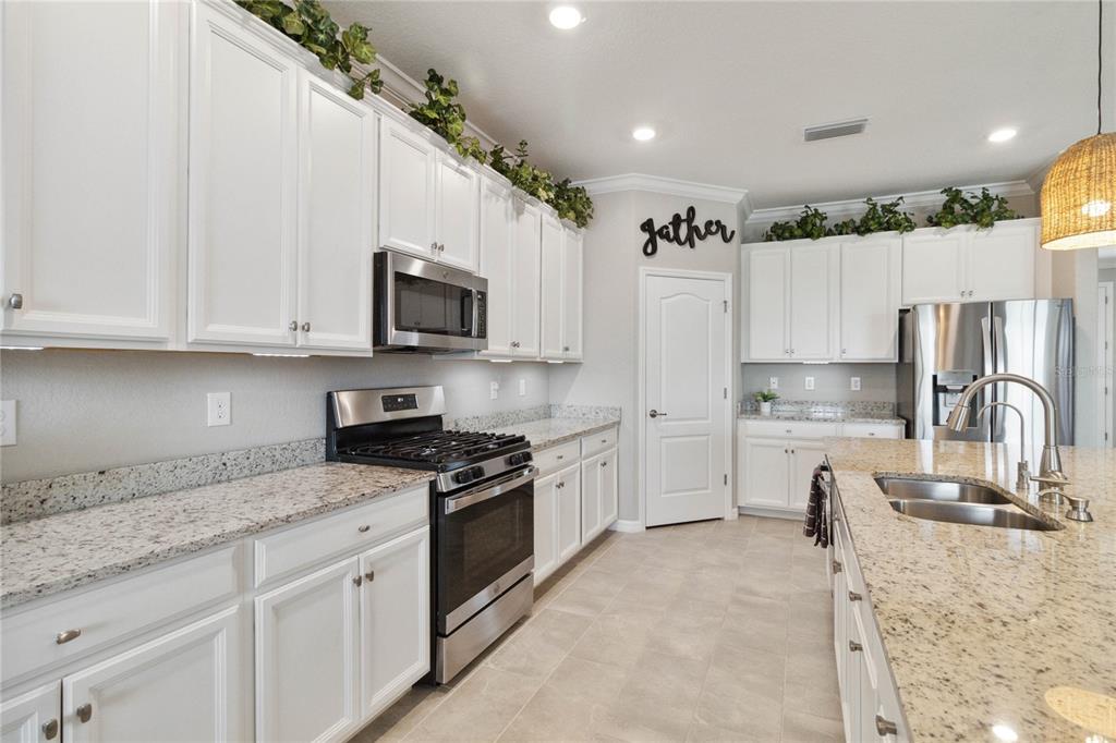 A kitchen features white cabinets, granite countertops, stainless steel appliances, and a central island — 17724 POLO TRAIL, LAKEWOOD RANCH, FL